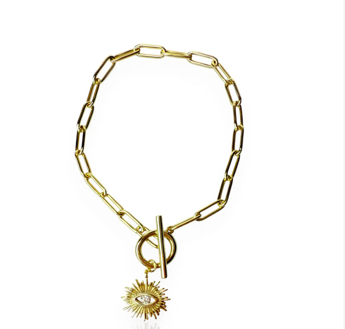 The Golden Eye Bracelet blends sleek design with symbolic detail. Crafted in 14k gold plated over silver, it features a bold paperclip chain and a front toggle clasp accented by a radiant sunburst charm set with a clear crystal eye. Polished and versatile, it brings a touch of strength and modern refinement to any style.
