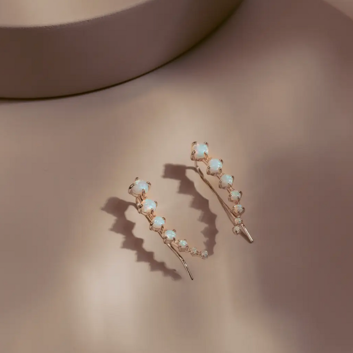 The Opal Arc Climbers follow the natural line of the ear with a graceful curve of glowing opals. Each stone reflects a soft play of color, set in 14k gold plated over silver for a clean polished finish. Refined and modern, they bring quiet radiance to any look.