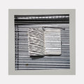The artwork 'Sentence Structure String 1' by Anne Sherwood Pundyk features a monochromatic composition with parallel horizontal lines creating a textured background. A central white rectangular form emerges, marked with abstract linear notations resembling text or musical notation. The piece combines stark black and white contrast in an archival inkjet print mounted on wood panel.